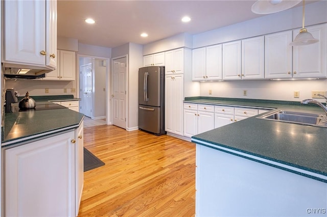 kitchen with a sink, white cabinetry, dark countertops, and freestanding refrigerator