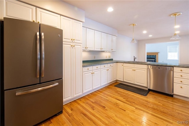 kitchen with light wood-style flooring, a sink, hanging light fixtures, stainless steel appliances, and white cabinetry