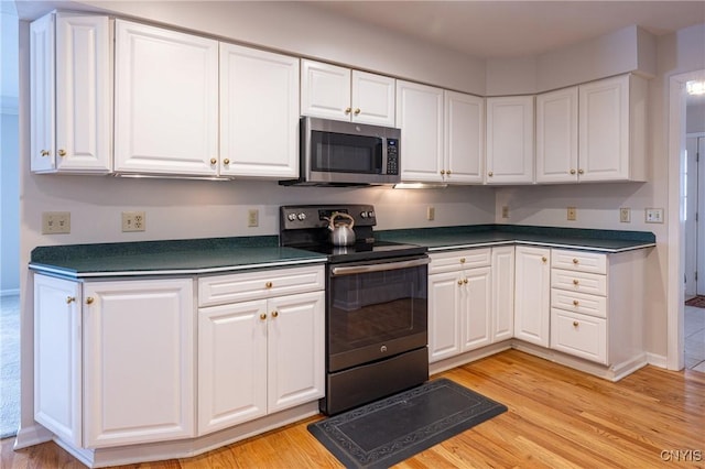 kitchen featuring stainless steel microwave, black / electric stove, dark countertops, and white cabinets