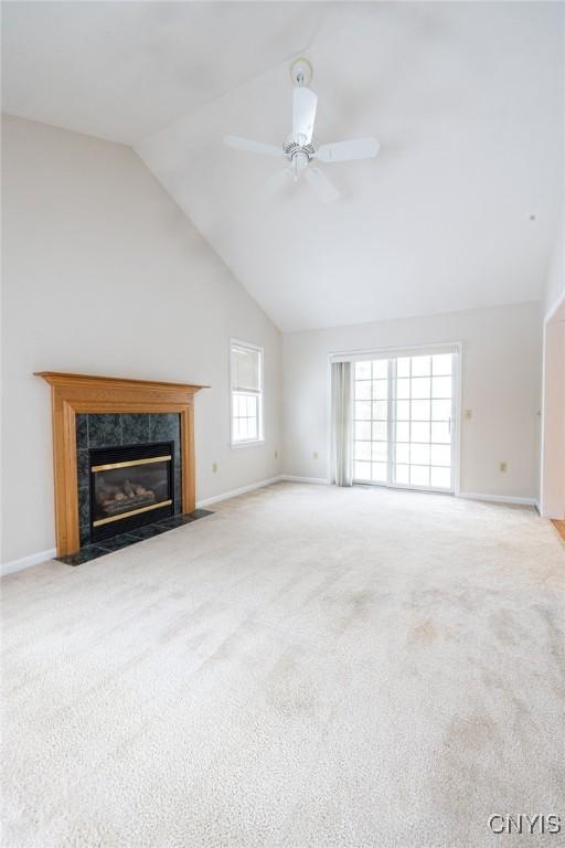 unfurnished living room featuring carpet flooring, baseboards, a ceiling fan, and a premium fireplace