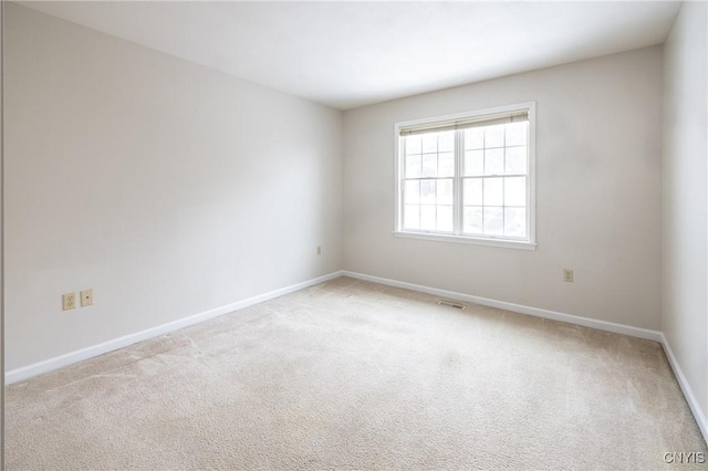 empty room with baseboards, visible vents, and light carpet