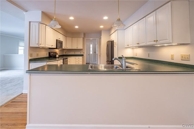 kitchen featuring a sink, dark countertops, a peninsula, and stainless steel appliances