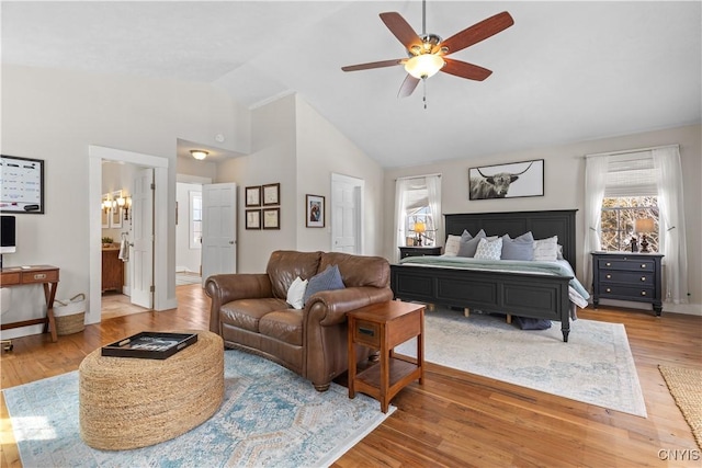 bedroom featuring high vaulted ceiling, ensuite bath, light wood finished floors, baseboards, and ceiling fan