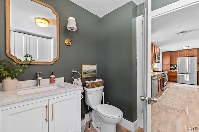 bathroom featuring vanity, toilet, wood finished floors, and baseboards