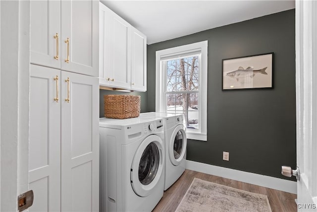 laundry area with cabinet space, light wood-style floors, baseboards, and separate washer and dryer