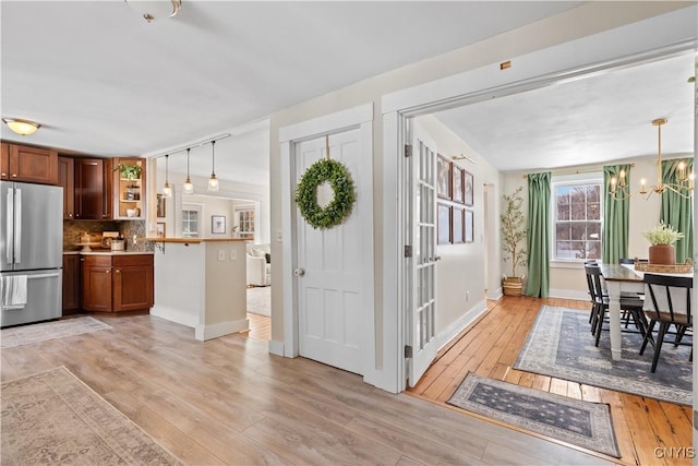 interior space featuring open shelves, light wood-style flooring, freestanding refrigerator, brown cabinets, and backsplash