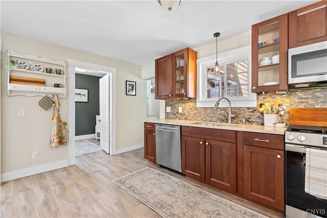 kitchen featuring tasteful backsplash, light countertops, appliances with stainless steel finishes, light wood-style floors, and a sink