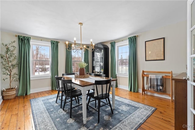 dining room with an inviting chandelier, a wealth of natural light, baseboards, and wood-type flooring