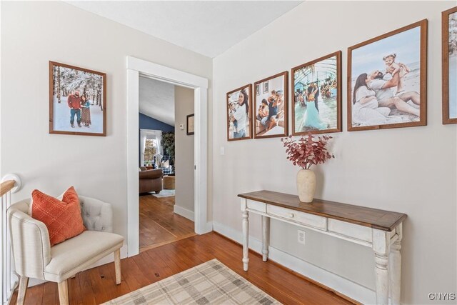 interior space featuring lofted ceiling, baseboards, and wood finished floors