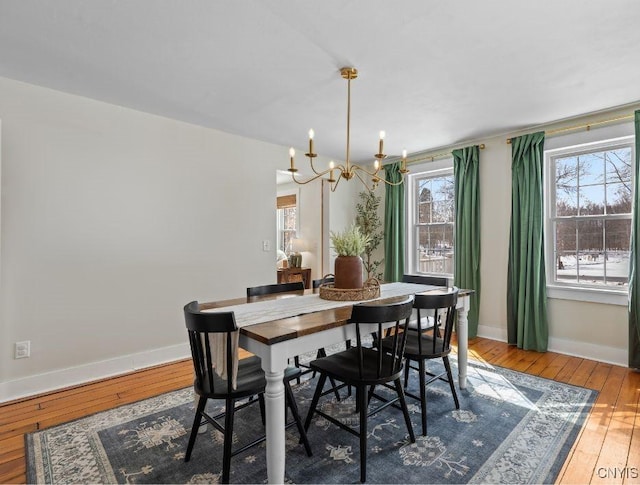 dining room with baseboards, wood-type flooring, and a notable chandelier