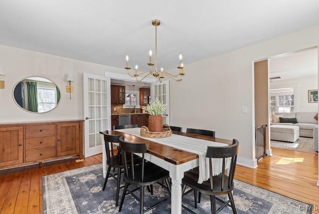 dining room with baseboards, an inviting chandelier, and hardwood / wood-style floors