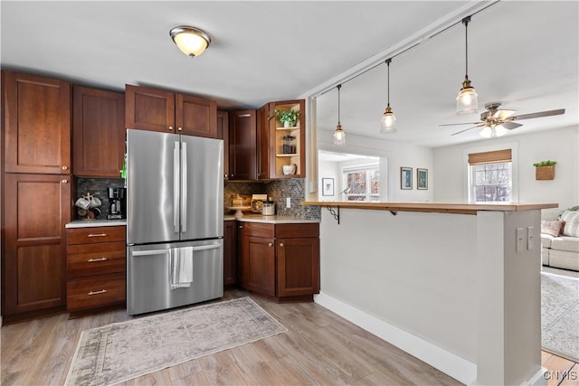 kitchen featuring open shelves, freestanding refrigerator, light wood-style floors, light countertops, and decorative backsplash