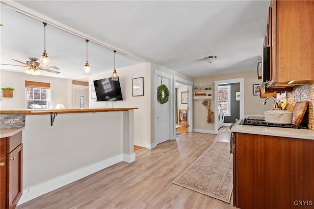 kitchen featuring brown cabinets, washer / clothes dryer, light countertops, light wood-style floors, and tasteful backsplash