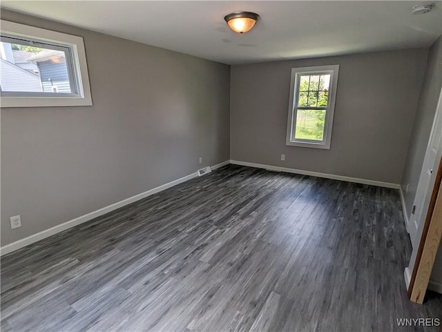 empty room with visible vents, baseboards, and dark wood finished floors