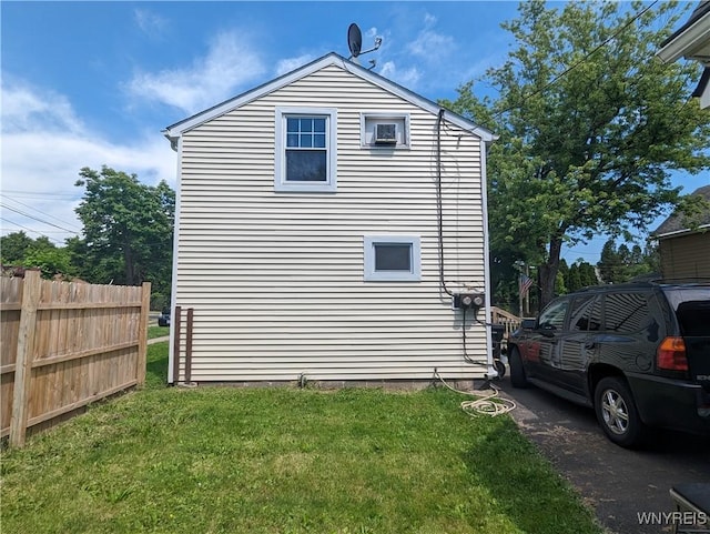 view of side of home with a yard and fence