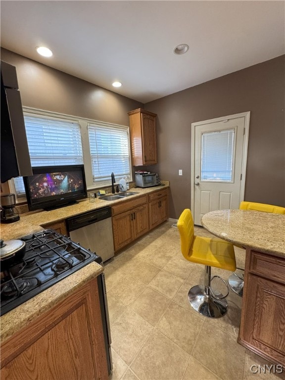 kitchen featuring a sink, recessed lighting, cooktop, brown cabinetry, and dishwashing machine