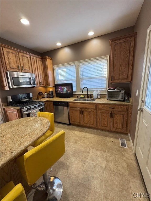 kitchen with light countertops, recessed lighting, brown cabinets, appliances with stainless steel finishes, and a sink