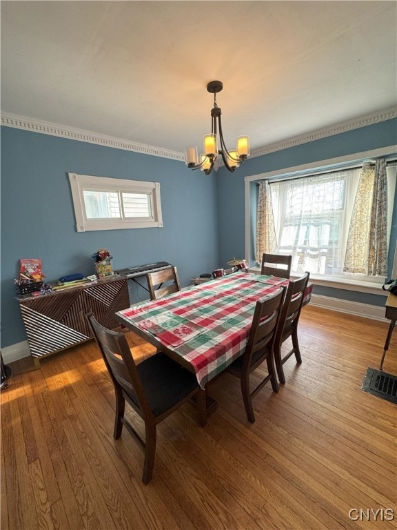 dining space with baseboards, a notable chandelier, a healthy amount of sunlight, and wood finished floors