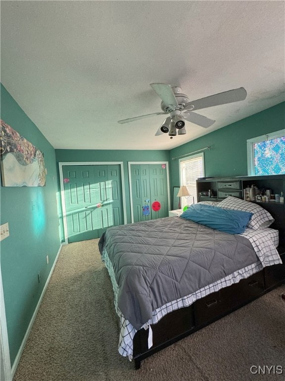 carpeted bedroom with baseboards, a textured ceiling, ceiling fan, and multiple closets