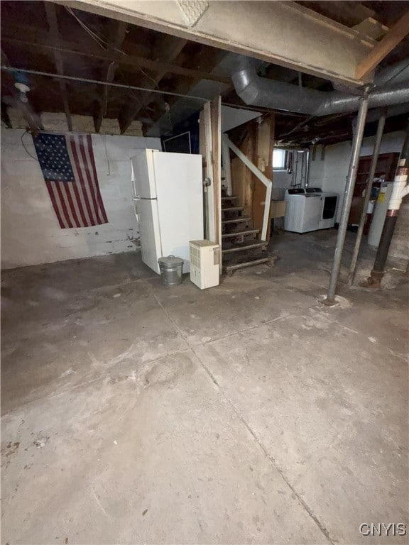 unfinished below grade area with stairs, washer / dryer, and freestanding refrigerator