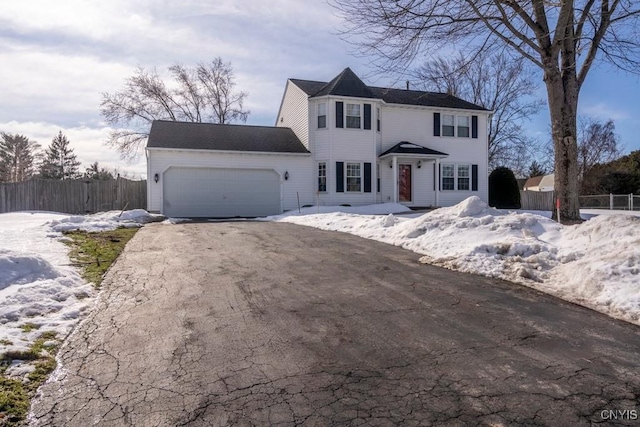 colonial house featuring aphalt driveway, fence, and a garage