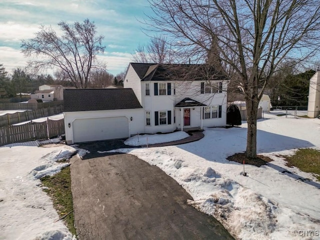 colonial house with an attached garage, driveway, and fence