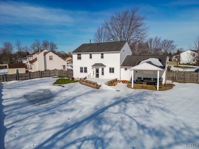 snow covered rear of property featuring a gazebo, an outdoor living space, and a fenced backyard