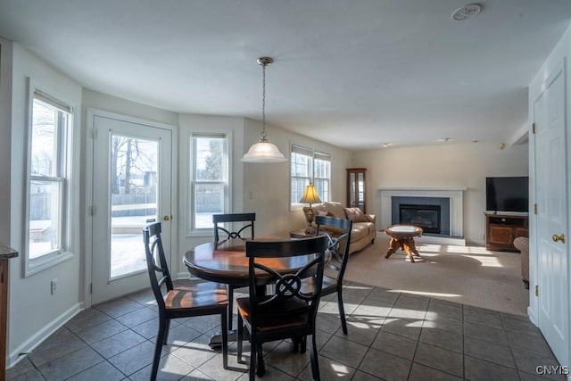 dining room featuring a glass covered fireplace and baseboards