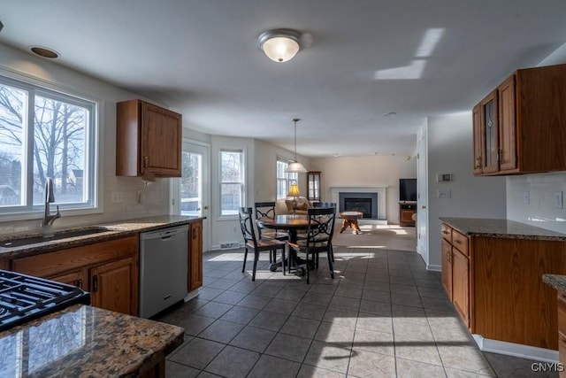 kitchen with decorative backsplash, dishwasher, a fireplace, and a sink