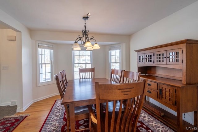 dining room with baseboards, a notable chandelier, and light wood finished floors