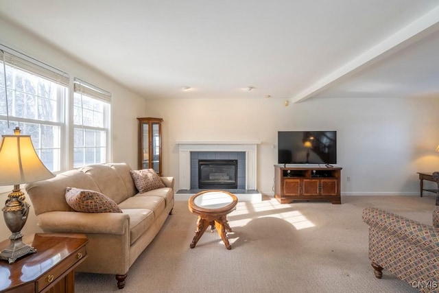 living area featuring beamed ceiling, baseboards, light colored carpet, and a tile fireplace