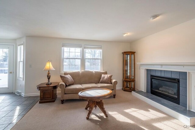 carpeted living room with a wealth of natural light, baseboards, a tile fireplace, and tile patterned flooring