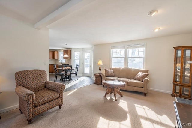 living area featuring baseboards, light colored carpet, and a healthy amount of sunlight