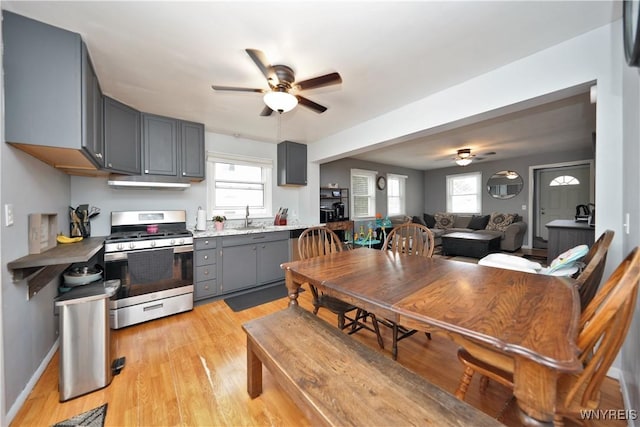 kitchen featuring gas stove, gray cabinetry, light wood-style flooring, and a ceiling fan