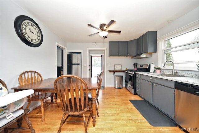 kitchen with light wood-style flooring, gray cabinetry, stainless steel appliances, and a sink