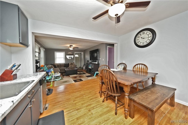 dining space with baseboards, light wood-type flooring, and ceiling fan