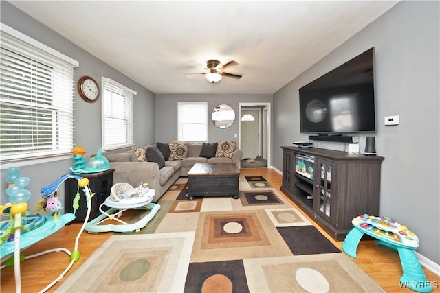 living area with baseboards, ceiling fan, and wood finished floors