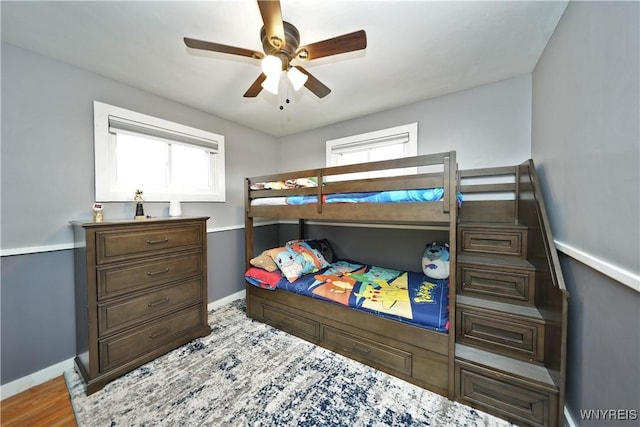 bedroom with baseboards, wood finished floors, and a ceiling fan