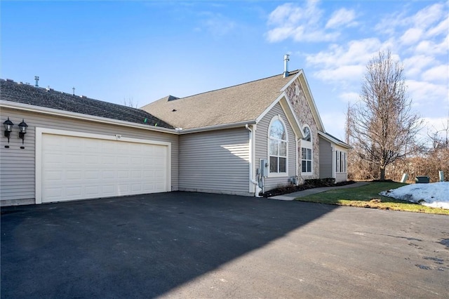 view of property exterior featuring aphalt driveway, a yard, and an attached garage