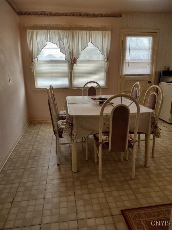 dining area with wallpapered walls and washer / clothes dryer