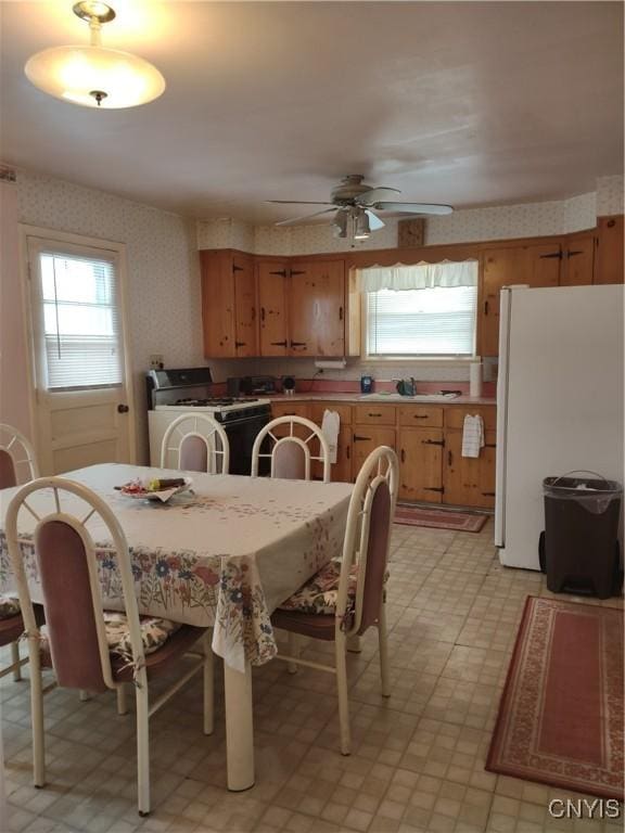 dining room with plenty of natural light, light floors, a ceiling fan, and wallpapered walls