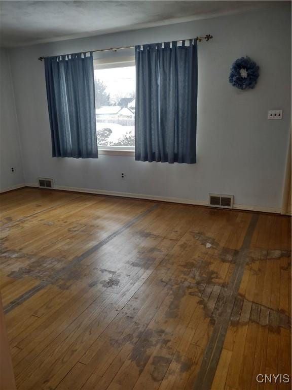 empty room featuring visible vents and hardwood / wood-style floors