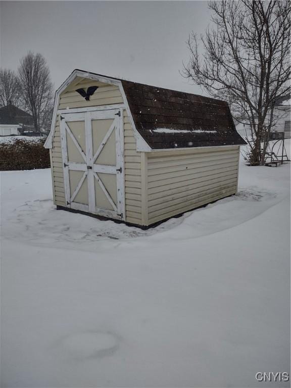 snow covered structure with an outbuilding and a shed