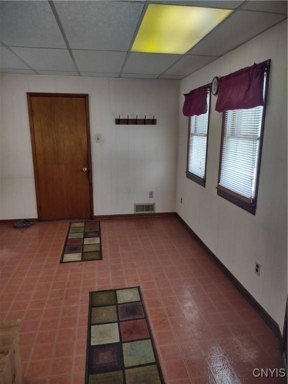 unfurnished room featuring baseboards, visible vents, and a drop ceiling