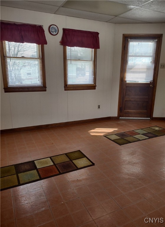 foyer entrance featuring a paneled ceiling and baseboards