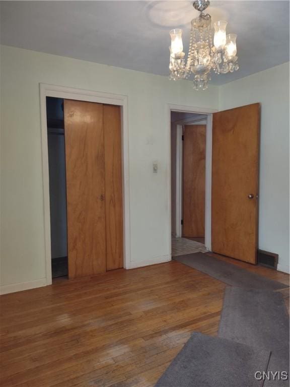 interior space featuring visible vents, a notable chandelier, wood finished floors, a closet, and baseboards