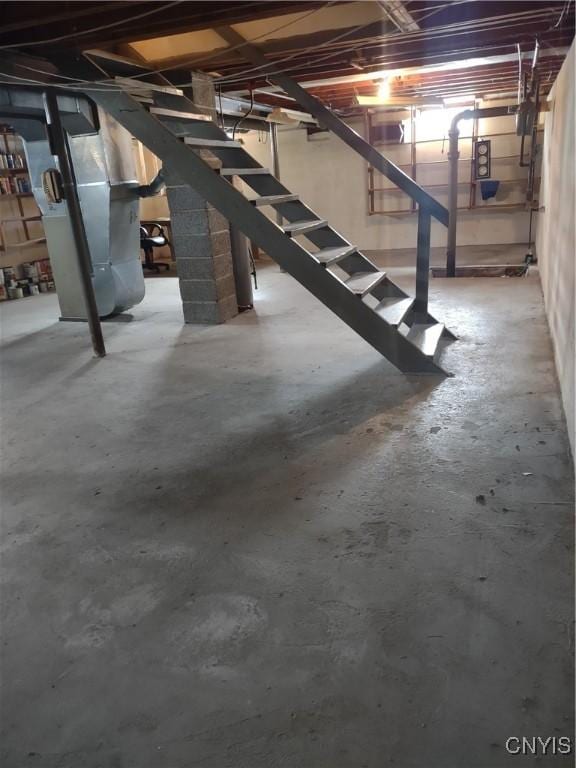 unfinished basement featuring stairway and heating unit