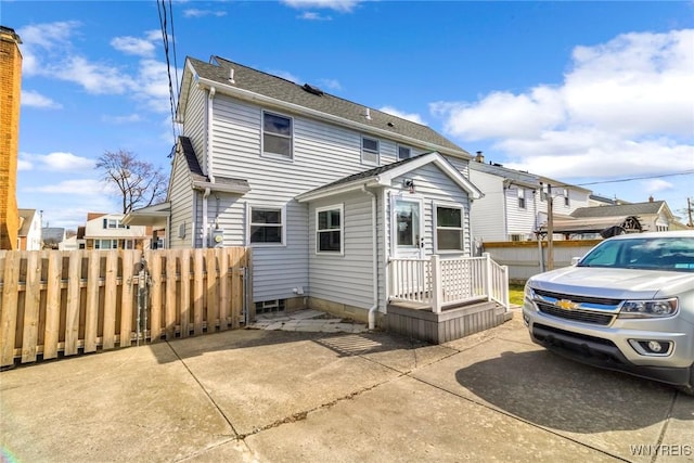 rear view of property with roof with shingles and fence