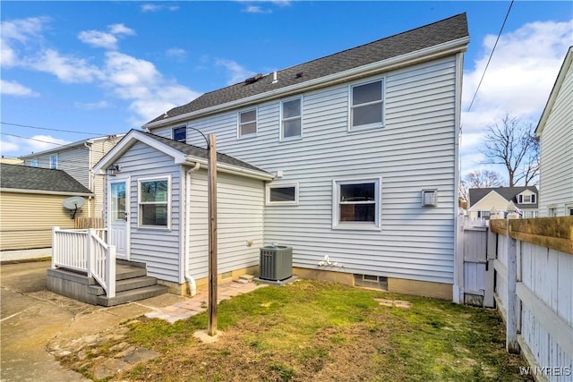 back of house featuring central air condition unit, a yard, and fence