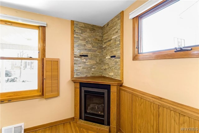 bar featuring visible vents, wood finished floors, a glass covered fireplace, and wainscoting